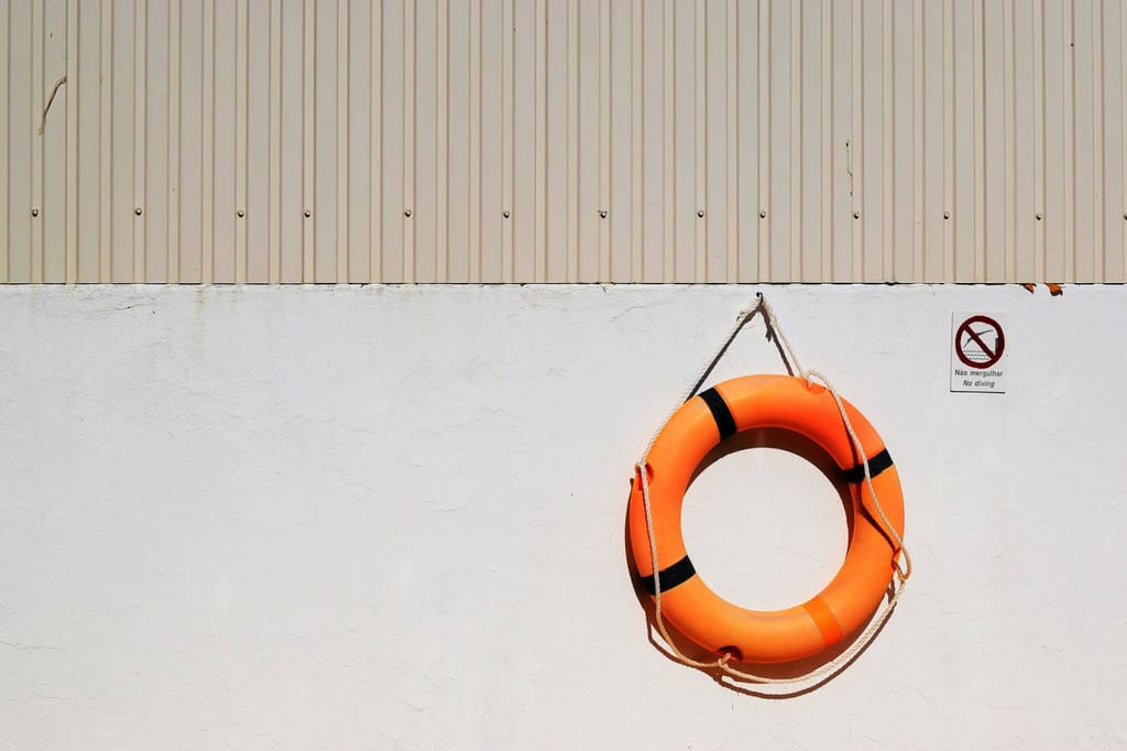 An orange life preserver hanging on a concrete wall.