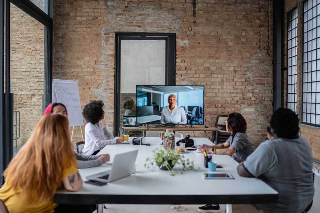 A team conducting a meeting with remote coworkers using remote work software.