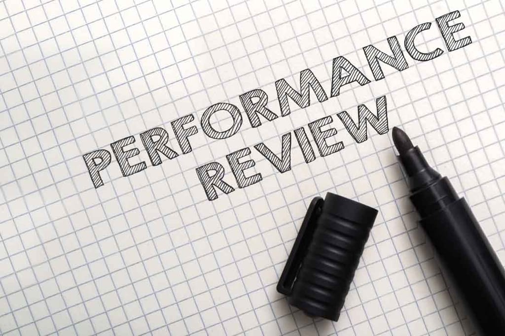 A pen and paper with the word performance review, which is an old way to identify high-performance employee behaviors.