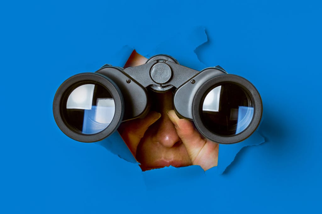 A person looking through a hole in a wall using binoculars to symbolize workforce forecasting