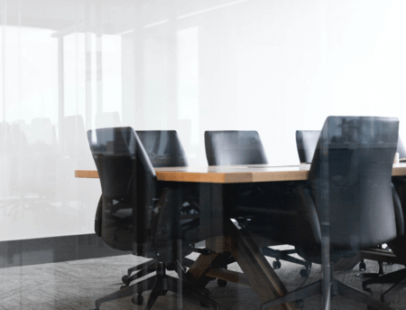 An empty conference room with black chairs at the conference table.