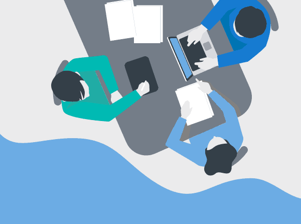 Seen from above, 3 people working at a table with a laptop, tablet, smart phone, folders and papers.