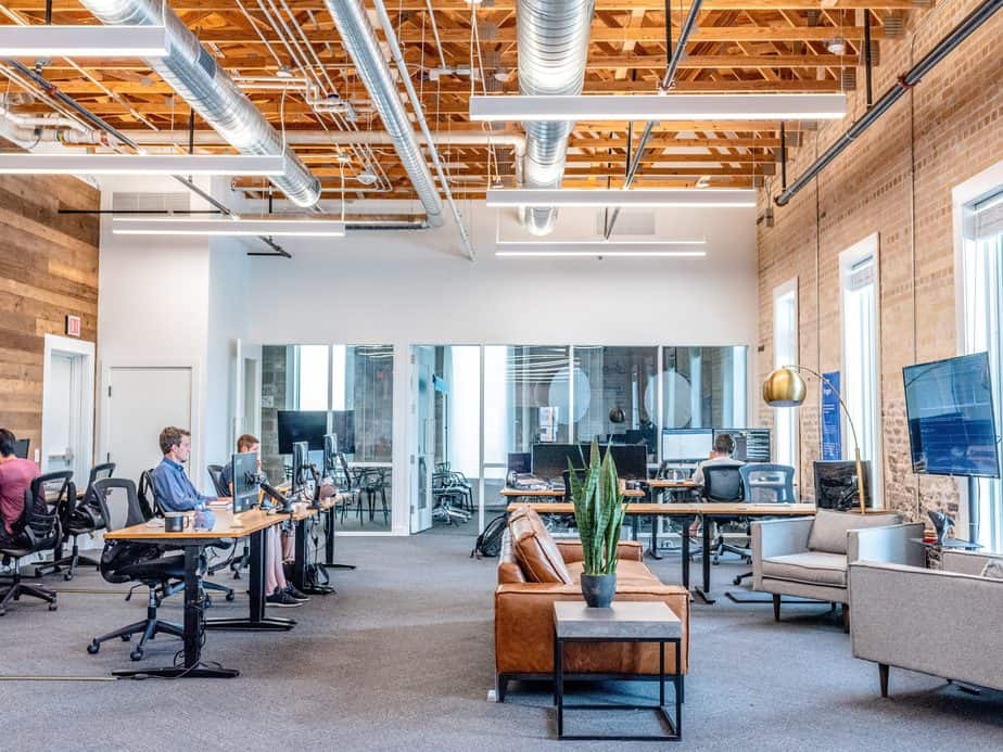 A large, open office space with several desks and 3 men working.