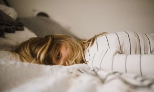 A woman laying in her bed with her hair covering her face