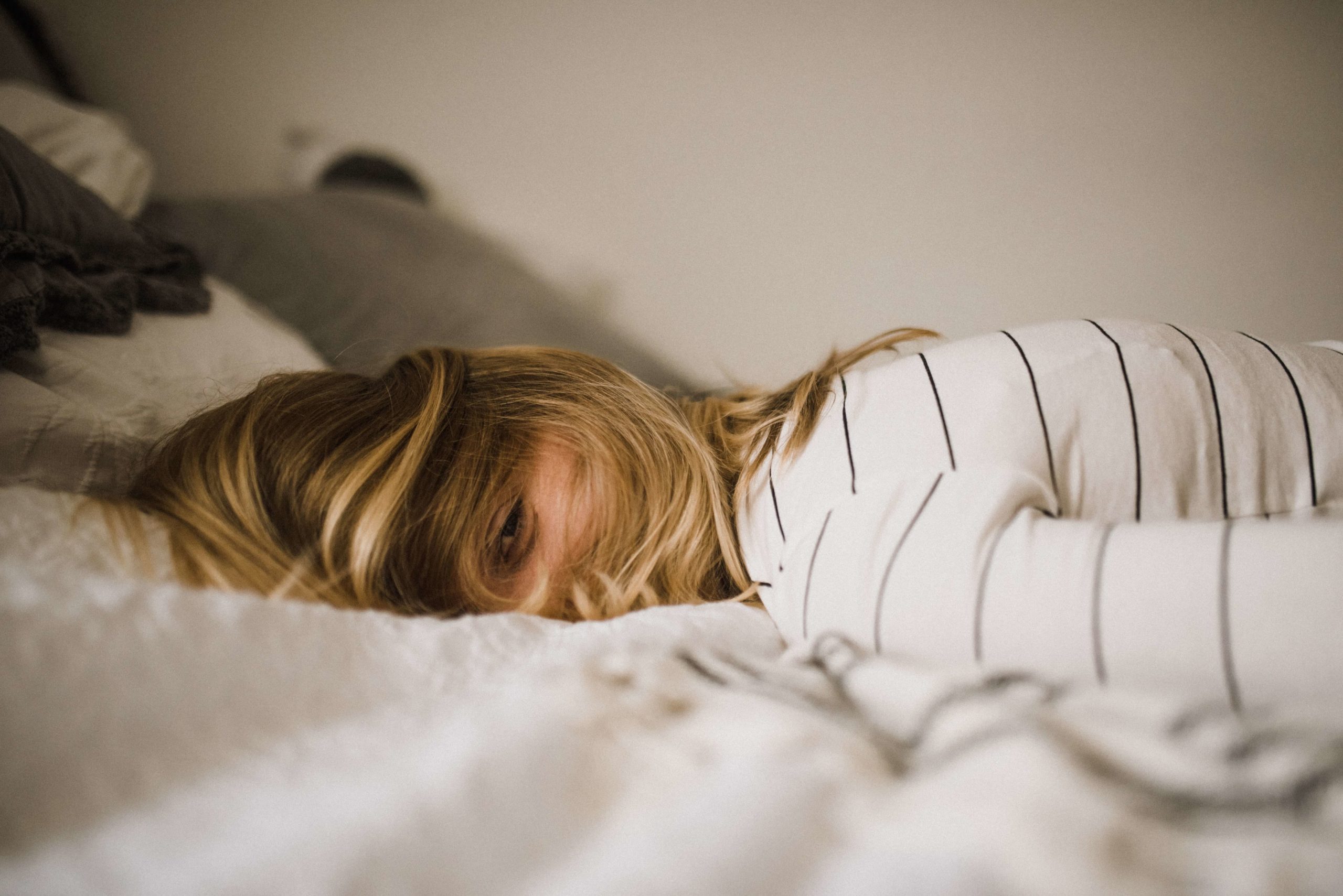 A woman laying in her bed with her hair covering her face