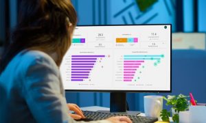 A woman pointing to charts and reports showing productivity trend last 12 complete weeks with a lightbulb and gear icons.