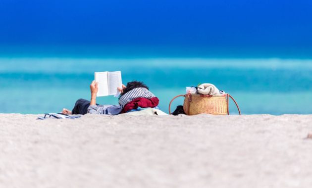 Summer Reading List: Person reading on the beach