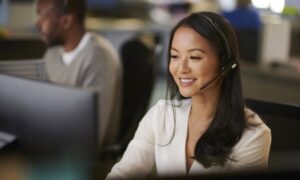 Woman wearing a headset engaged in a conversation while being productive at a call center.