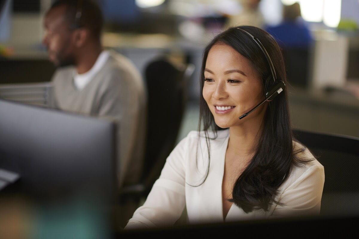 Woman wearing a headset engaged in a conversation while being productive at a call center.