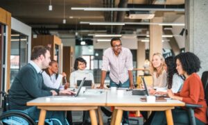A team meeting at a large table discussing questions like what is productivity in business? Is this meeting productive? Where does our lost productivity go?