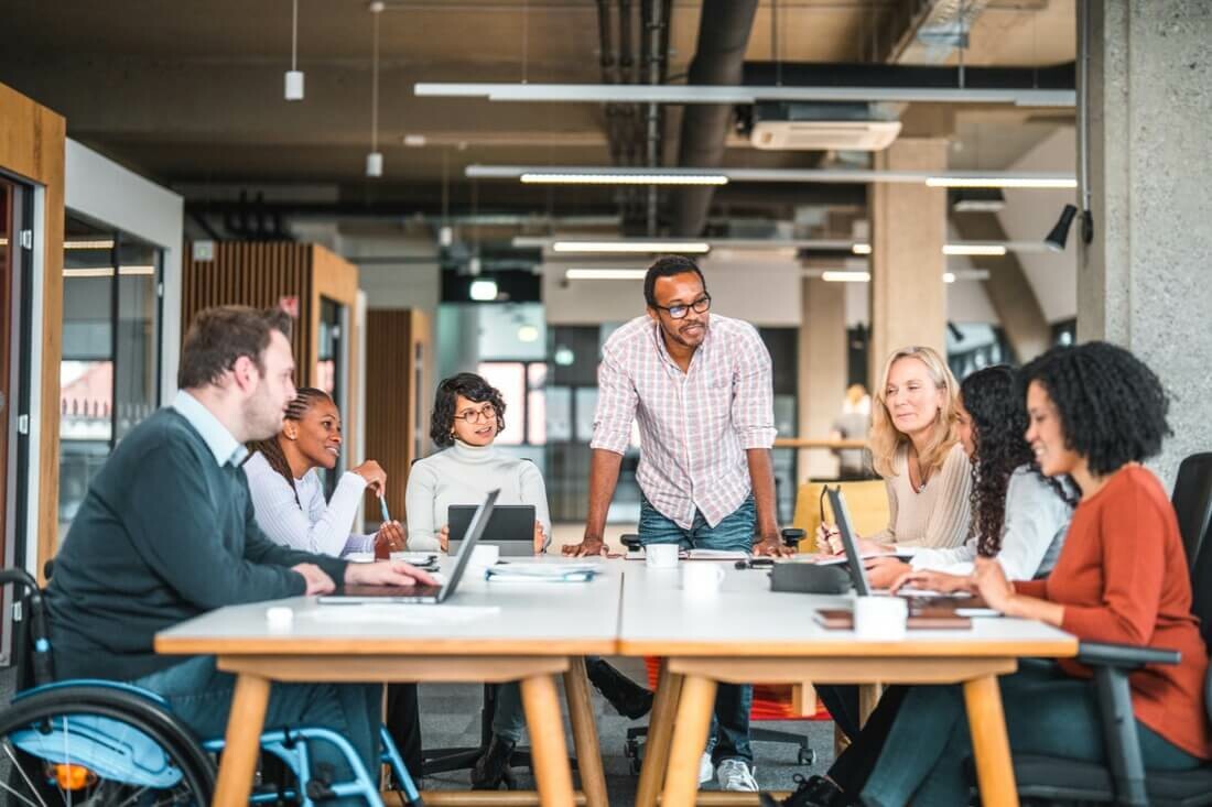 A team meeting at a large table discussing questions like what is productivity in business? Is this meeting productive? Where does our lost productivity go?