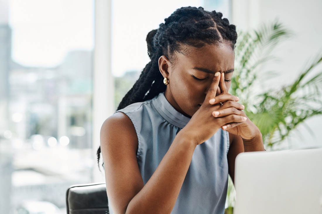 An employee looking at their computer being overwhelmed and burnt out