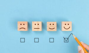4 wooden blocks showing different emotions to represent levels of high or low employee engagement.