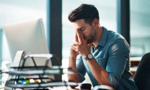 An overworked manager in his office brainstorming solutions for overworked employees.
