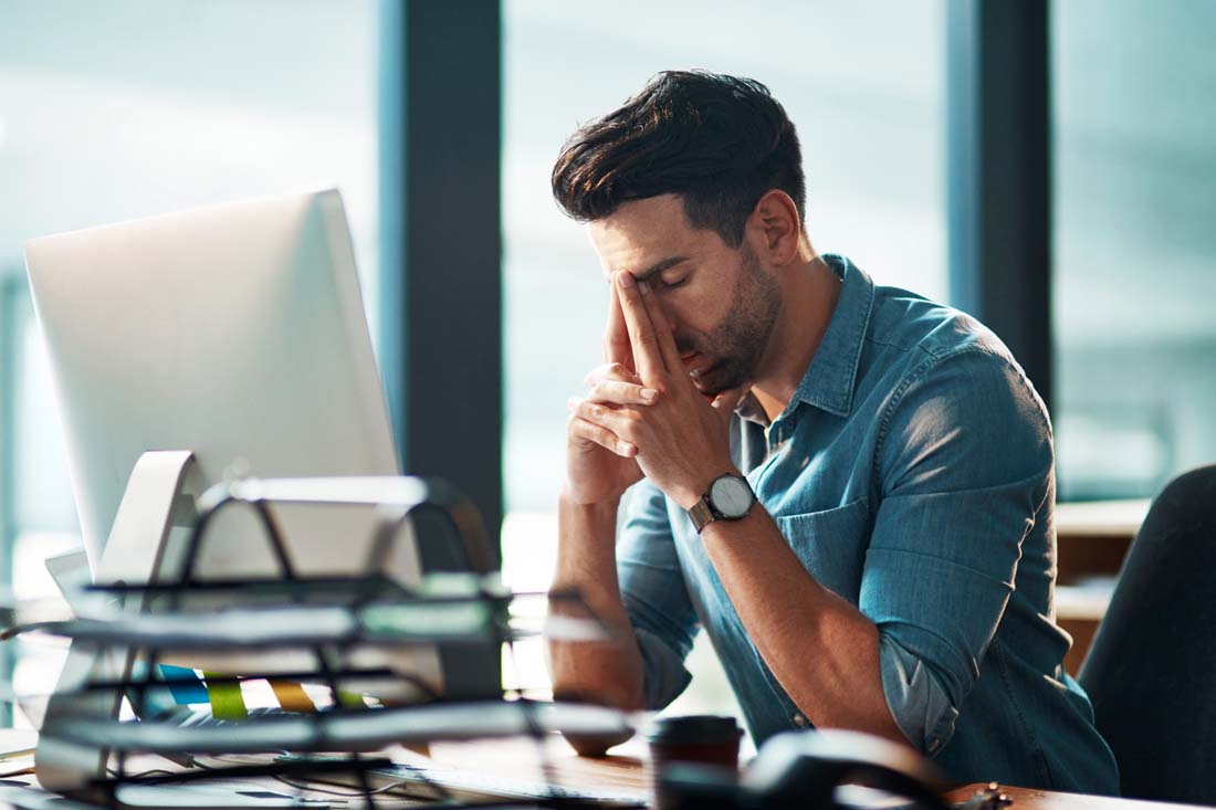 An overworked manager in his office brainstorming solutions for overworked employees.