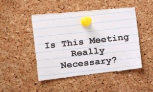 A note card with the words “is this meeting really necessary?” because meetings are common distractions in the workplace.