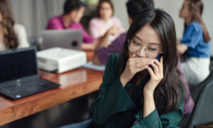 Woman whispering on a phone after being disrupted in a workplace meeting