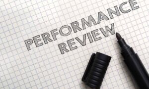 A pen and paper with the word performance review, which is an old way to identify high-performance employee behaviors.