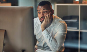 Employee staring at his computer looking bored because there’s not enough work