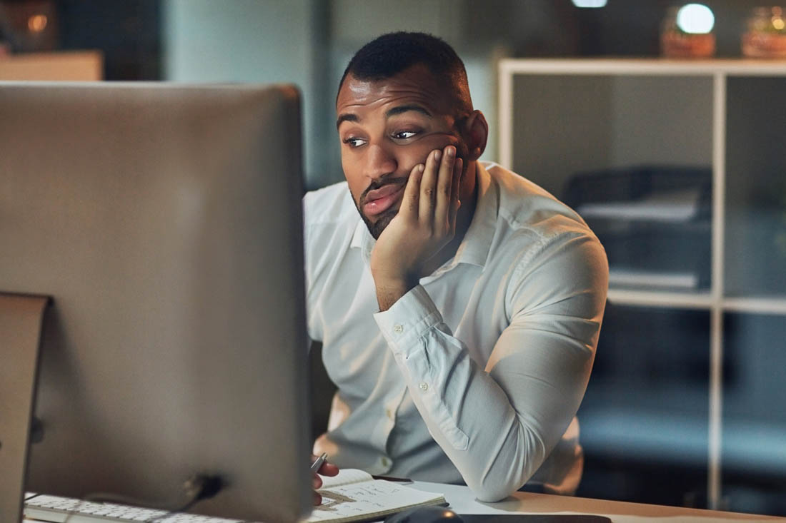 Employee staring at his computer looking bored because there’s not enough work