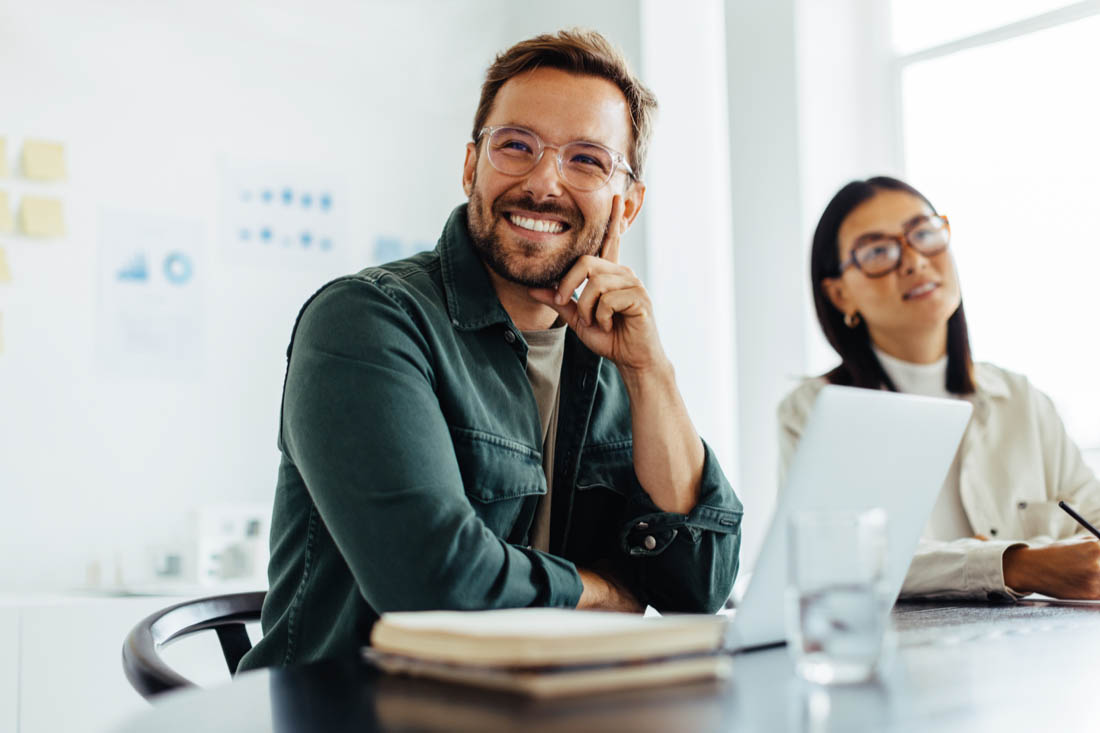 An employee in front of his laptop, happy about the benefits of increased productivity in the workplace