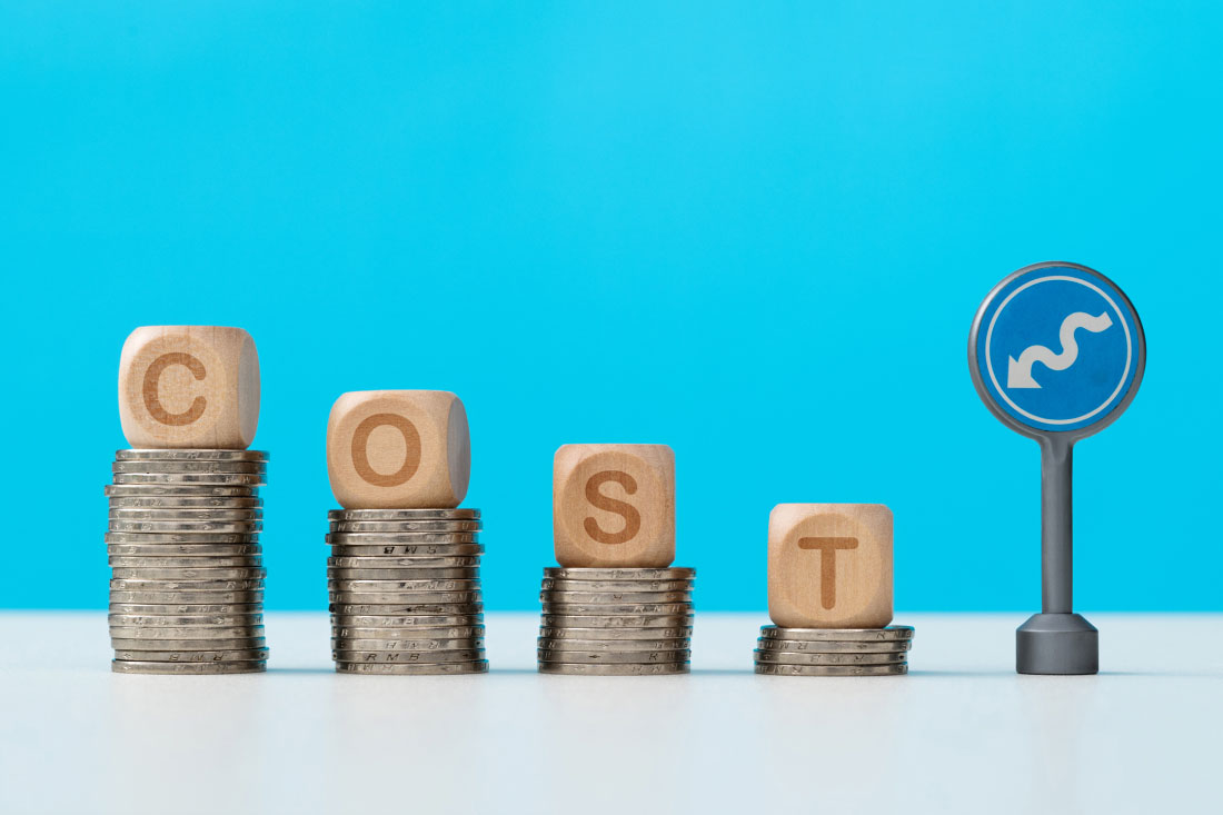 The word cost spelled in blocks on descending stacks of coins to signify business cost savings.