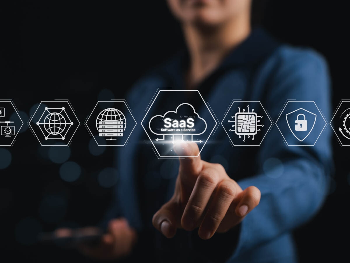 A person in a suit interacts with a glowing SaaS icon on a digital interface, surrounded by tech-related symbols, conveying innovation and technology.