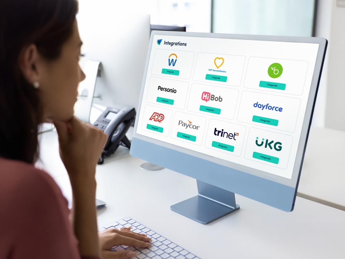 Executive looks at computer screen filled with icons of ActivTrak HRIS integrations, including Workday, UKG and more.